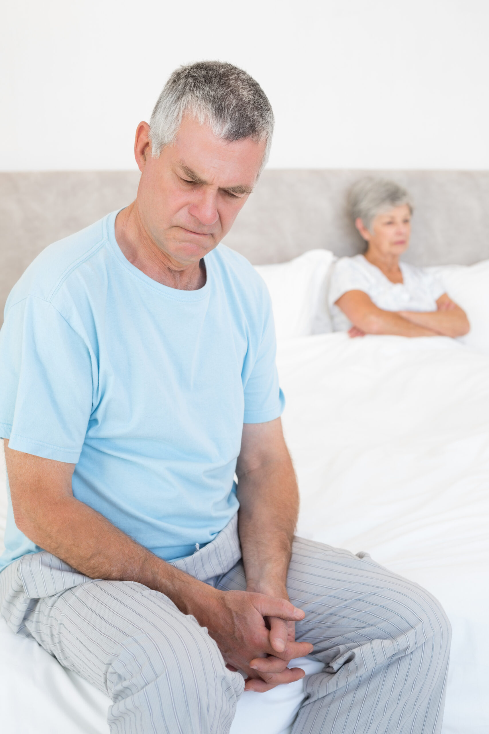 sad-senior-man-bed-with-wife-background